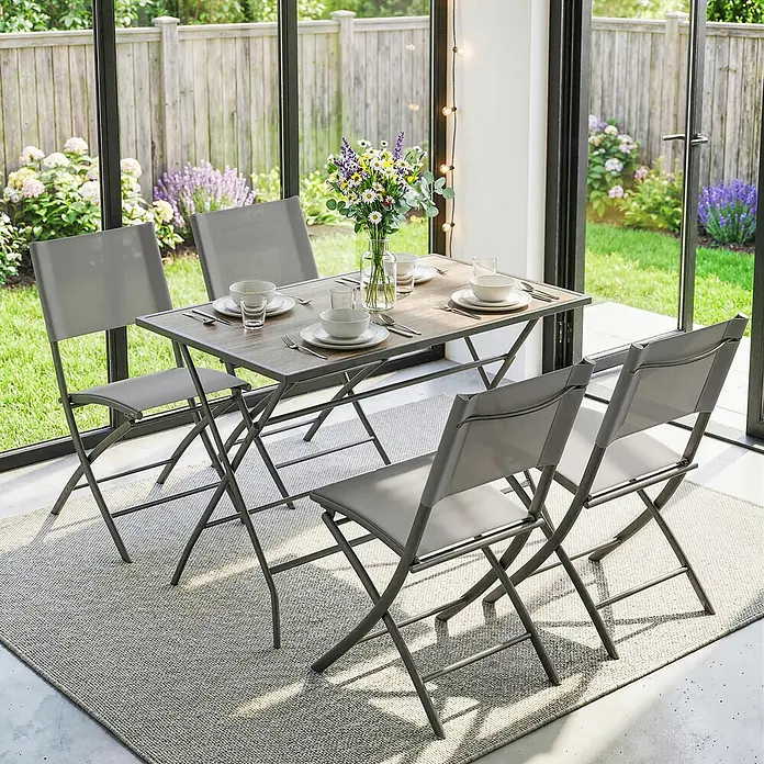 Outsunny Gartentisch-Set - Gesamtumfang: 5 -tlg., Stahl, Netzstoff, Kunststoff, Klappbar - Ein klappbares Ess-Set aus grauem Metall und Holzoptik mit vier Stühlen auf einem Teppich in einem Wintergarten mit Gartenblick.