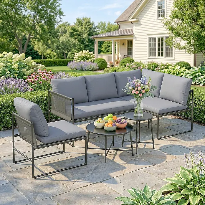 Outsunny Loungemöbel-Set - 5 -tlg., Stahl, Netzstoff, Polyester, Schaumstoff, PP-Baumwolle, Dunkelgrau - Graues Outdoor-Ecksofa und Sessel mit dunklen Metallrahmen und schwarzen Tischen, auf einer Steinterrasse in einem Garten.
