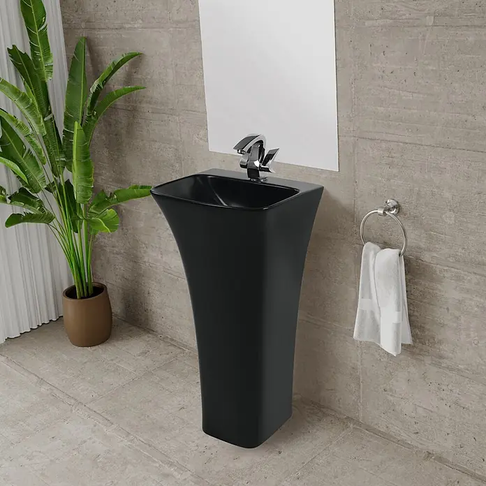 Sanicomfort Opia Waschtisch - 41 x 38 cm, Ohne Spezialglasur, Hahnloch: Mitte, Ohne Überlauf, Schwarz, Hahnloch vorgestochen - für Wand- oder Standarmaturen geeignet - Moderne schwarze Standsäule mit Chromarmatur in einem modernen Bad, von einer Grünpflanze flankiert.