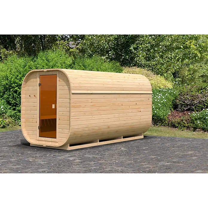 Karibu Saunahaus Quadro 3 - Ohne Ofen, Natur, L x B x H: 355 x 199 x 205 cm - Fasssauna aus hellem Holz mit dunkler Glastür, auf einer gepflasterten Terrasse in einem üppigen Garten.