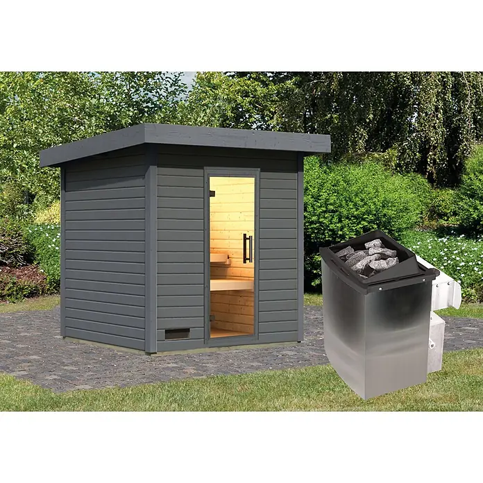 Karibu Saunahaus Kaapi 3 - 9 KW Ofen mit interner Steuerung, Terragrau, L x B x H: 196 x 196 x 228 cm - Graue Außensauna mit offener Tür, die Holzinterieur zeigt, und schwarzer Saunaofen mit Steinen auf gepflasterter Terrasse im Garten.