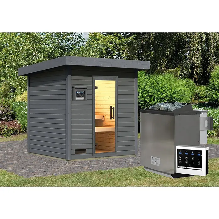Karibu Saunahaus Kaapi 3 - 9 KW Bio-Ofen mit externer Steuerung, Anthrazit, L x B x H: 196 x 196 x 228 cm - Dunkelgraue Holz-Außensauna mit offener Tür, hellem Holzinterieur, neben Edelstahl-Saunaofen mit Steinen und weißem Bedienfeld, auf Pflastersteinen im Garten.