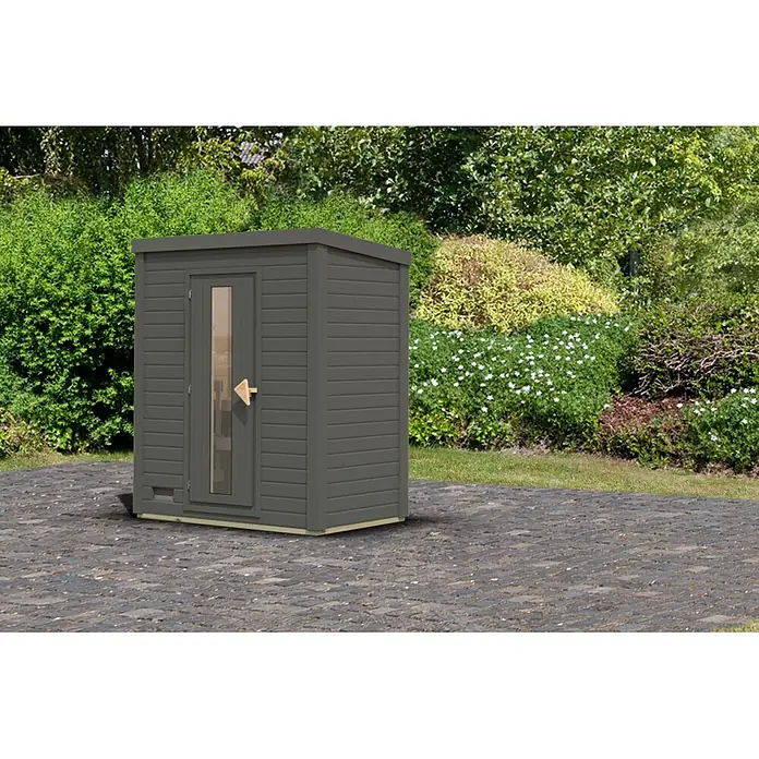 Karibu Saunahaus Hytti - Ohne Ofen, Terragrau, L x B x H: 113 x 196 x 228 cm - Dunkelgraue Außensauna mit Glastür auf einer gepflasterten Terrasse im Garten.