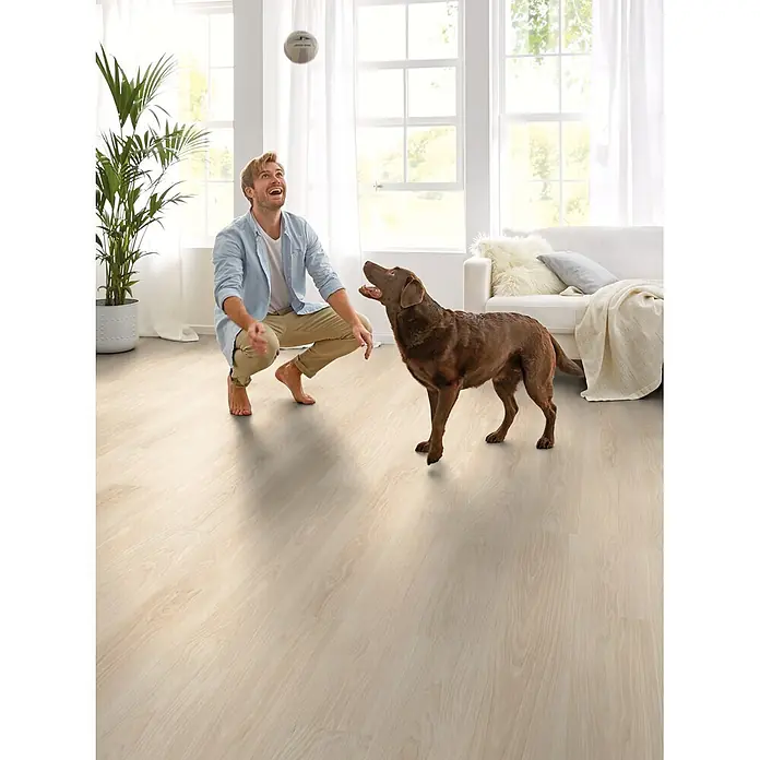 Decolife Designboden Freestyle - Oak Classic White, Landhausdiele, 1.220 x 185 x 8 mm - Helle Holzfussbodendielen in einem hellen Wohnbereich mit einem Mann und seinem Hund.