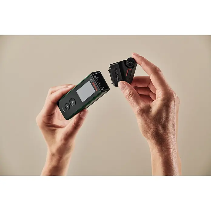 Bosch Laserentfernungsmesser Zamo Set - Messbereich: 0,15 - 40 m, 7 -tlg. - Hände verbinden schwarzen Adapter mit grün-schwarzem Bosch Zamo Laserentfernungsmesser.