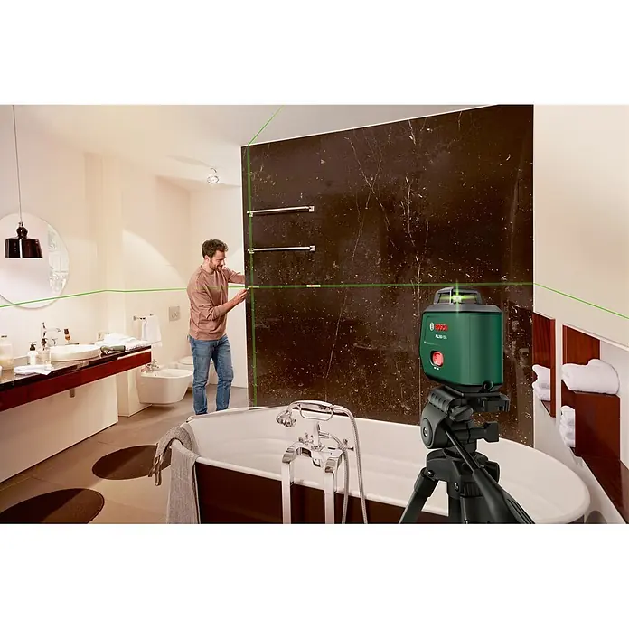 Bosch Kreuzlinienlaser PLL360-15G Set - Max. Arbeitsbereich: 30 m, 1 Akku, 3,6 V - Grüner Bosch PLL 360 15G Kreuzlinienlaser auf Stativ, projiziert Linien im Bad, während ein Mann Handtuchstangen montiert.