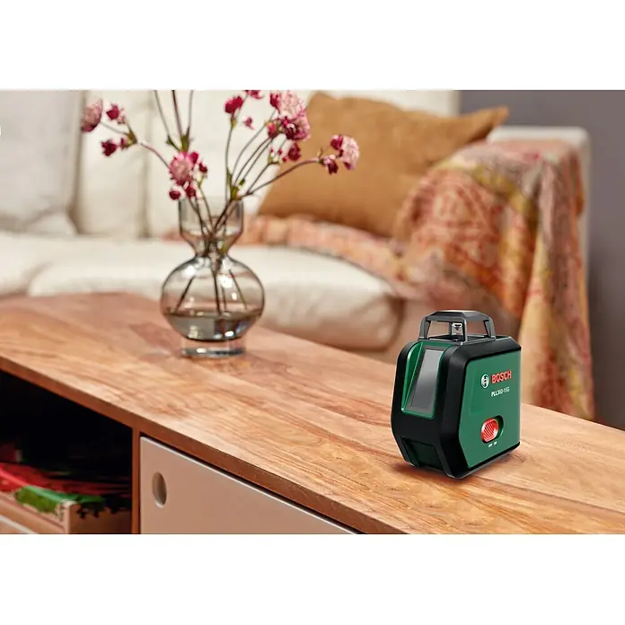 Bosch Kreuzlinienlaser PLL360-15G Set - Max. Arbeitsbereich: 30 m, 1 Akku, 3,6 V - Grüner und schwarzer Bosch PLL360-15G Linienlaser auf einem Holztisch im Wohnzimmer.