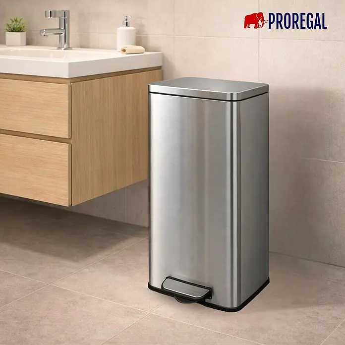 PROREGAL Mülleimer Küche Bad 60L, Abfalleimer mit Softclose & Stay-Open Deckel, Fußpedal & Inneneimer | Stahl, Silber | rechteckiger Treteimer mit Inneneimer, Tretmülleimer 60 Liter -  - Rechteckiger Treteimer aus Edelstahl mit schwarzem Sockel und Fußpedal, auf Fliesenboden im Bad neben einem Holzwaschtisch.