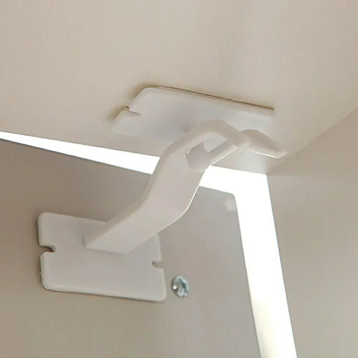 Dreambaby Extra-Lock - 2 Stk., Kleben - Nahaufnahme einer weißen Schranksicherung, die an einem Schrank befestigt ist, um die Kindersicherheit zu gewährleisten.