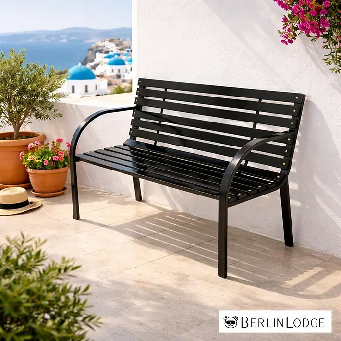Berlinlodge Gartenbank SANTORINI 2-Sitzer - Lackiert|Pulverbeschichtet, Schwarz - Schwarze Gartenbank aus Metall mit Lattenrost auf einem Balkon mit Meerblick und weißen Häusern.