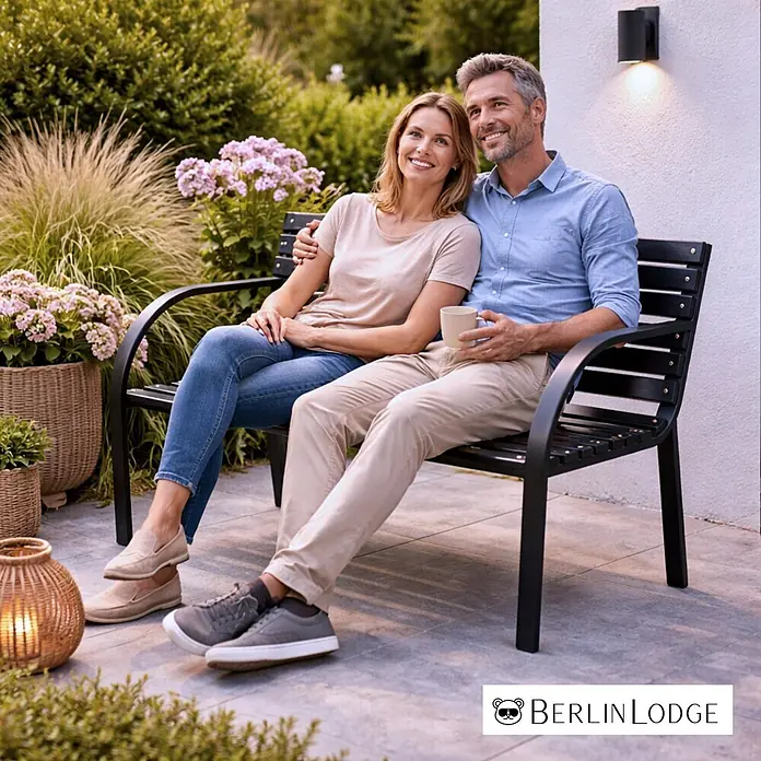 Berlinlodge Gartenbank SANTORINI 2-Sitzer - Lackiert|Pulverbeschichtet, Schwarz - Schwarze Metall-Gartenbank mit Holzlatten, von einem Paar im Garten genutzt.