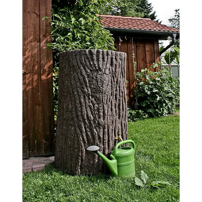 Arves Regenspeicher Evergreen - 475 l, Dunkelbraun, 1 Stk. - Regenwasserfass in Baumstammoptik mit einer grünen Gießkanne davor auf einem Rasen.