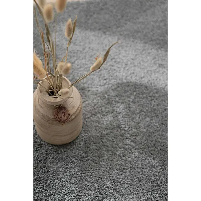 Bricoflor Teppichfliese - Breite: 50 cm, Velours, grau - Helle Keramikvase mit Trockenblumen und dekorativem Anhänger, auf dunklem Teppich.