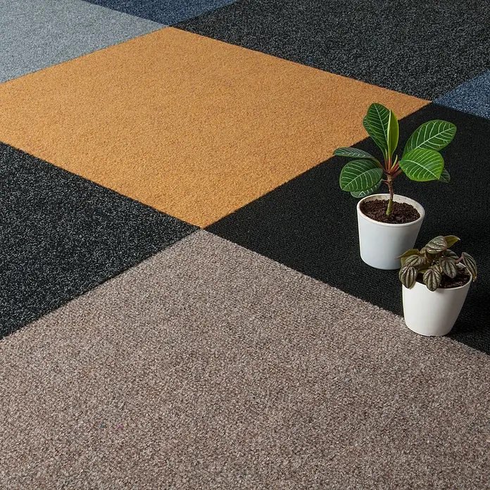 Bricoflor Teppichfliese - Breite: 50 cm, Nadelfilz, Polypropylen, braun - Geometrische modulare Teppichfliesen in Gelb, Grau und Beige, mit zwei Topfpflanzen auf dem Boden.
