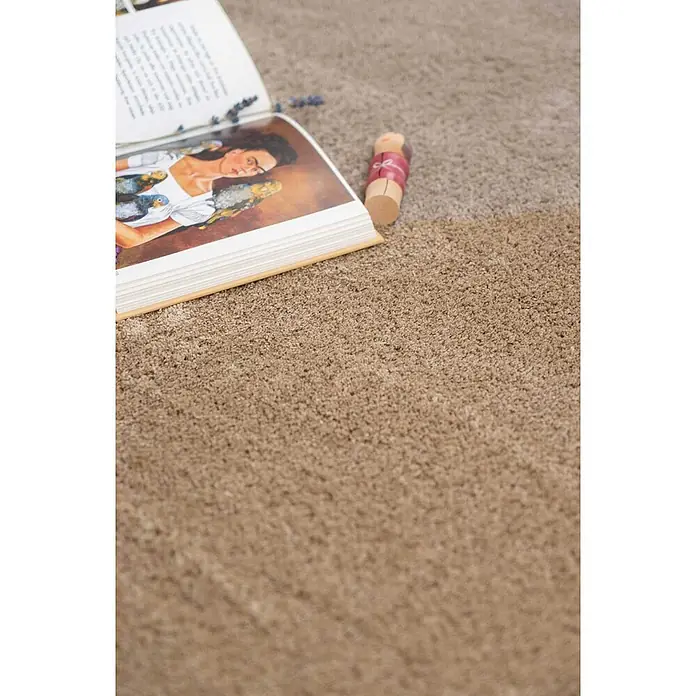 Bricoflor Teppichfliese - Breite: 50 cm, Velours, grau - Hellbrauner Hochflor-Teppich mit einem offenen Buch und einer Holzfigur darauf.