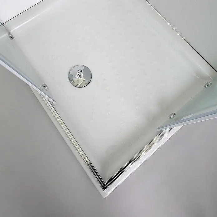 Kiamami Valentina Eckdusche - 900 x 700 x 1.900 cm, Farblos, Stärke: 6 mm - Weiße Duschwanne mit rutschfester Textur, Chromablauf und Teilansicht einer Glasduschwand.