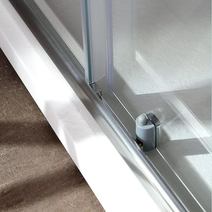 Kiamami Valentina Eckdusche - 750 x 750 x 1.850 cm, Transparent, Stärke: 4 mm - Untere Führungsschiene aus Silbermetall und graue Kunststoffführung für eine Duschschiebetür auf weißer Duschwanne.