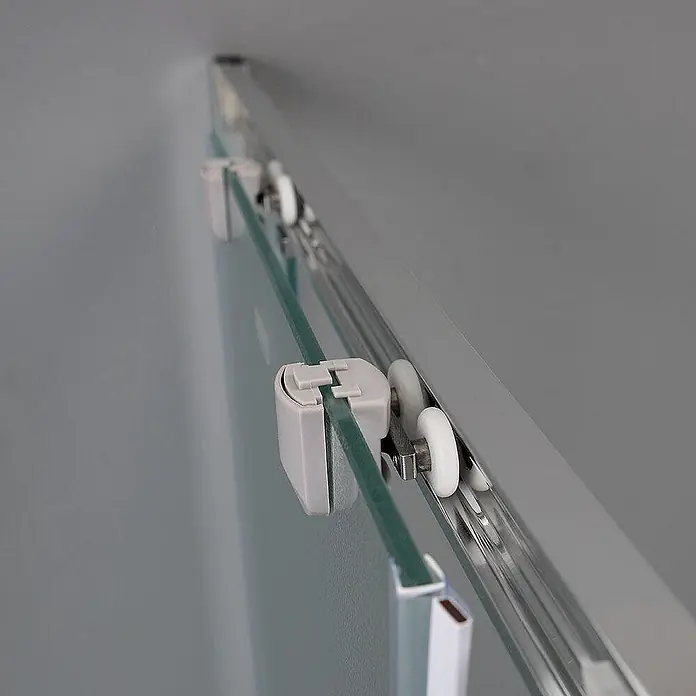 Kiamami Valentina Eckdusche - 1.200 x 700 x 1.850 cm, Matt, Stärke: 6 mm - Nahaufnahme der oberen Schiene einer Glasschiebetür mit weißen Rollen und Klemmen. Die Tür ist aus Klarglas, die Schiene silber.