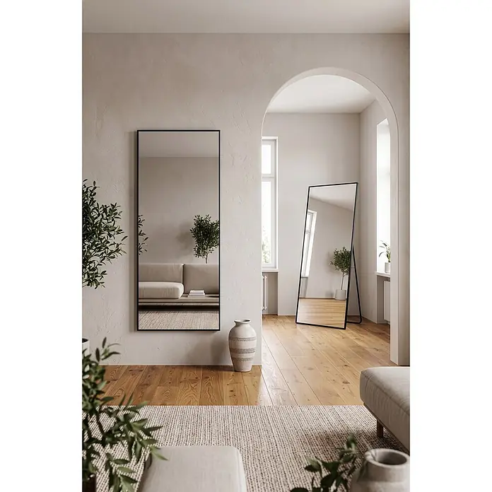 Standspiegel Mira - 70 x 170 cm, Eckig, Schwarz - Ein wandmontierter Spiegel mit schwarzem Rahmen und ein freistehender Ganzkörperspiegel mit schwarzem Rahmen in einem modernen Wohnzimmer.