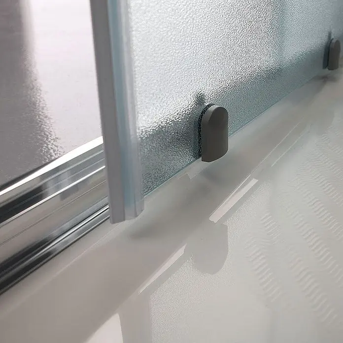 Kiamami Valentina Eckdusche - 900 x 900 x 1.850 cm, Matt, Stärke: 6 mm - Unterer Bereich einer Duschtür mit strukturiertem Glas, grauen Anschlägen und einer silbernen Laufschiene.