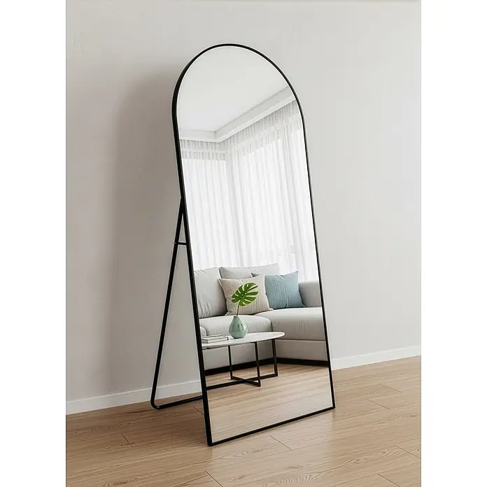 Standspiegel Mira - 70 x 170 cm, Gebogen, Schwarz - Ganzkörperspiegel mit schwarzem Metallrahmen, der einen Wohnzimmer-Innenraum widerspiegelt.