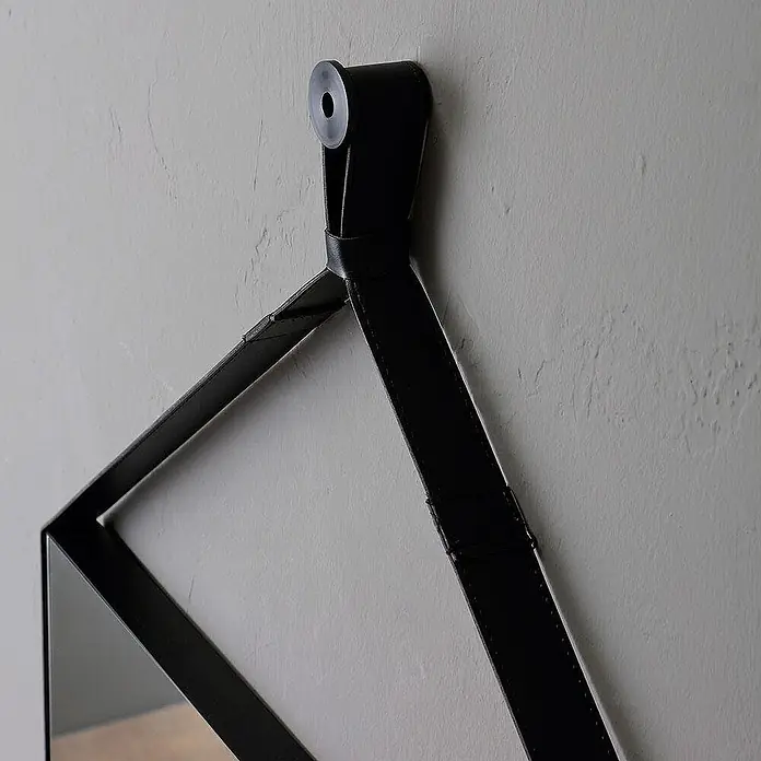 Kiamami Valentina Wandspiegel - 35 x 700 cm, Schwarz - Schwarzer Lederriemen hält einen geometrischen Spiegelrahmen an einem Wandhaken.
