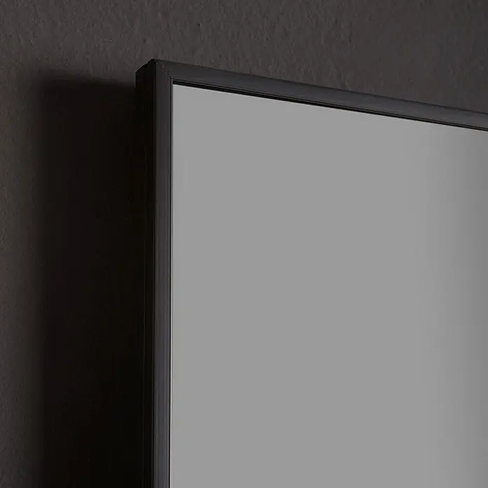 Kiamami Valentina Wandspiegel - 20 x 800 cm, Schwarz - Schwarz gerahmter Spiegel mit schlankem Design, an einer dunklen Wand lehnend.