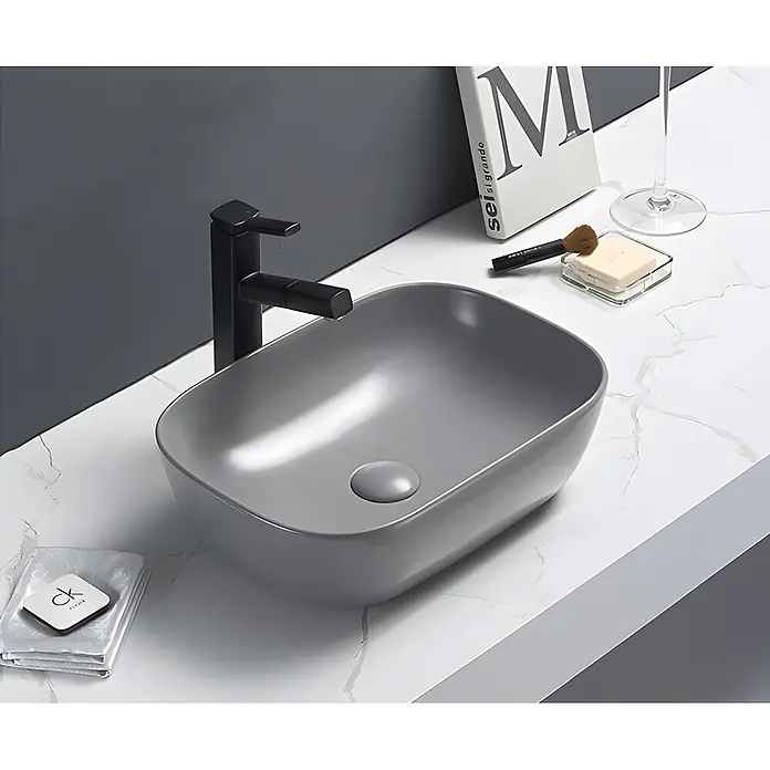 Sanicomfort Aufsatzwaschbecken Babu - 45,5 x 32,5 cm, Hahnloch: Ohne, Ohne Überlauf, Hellgrau - Modernes graues Keramikwaschbecken mit schwarzem Wasserhahn auf weißer Marmorplatte, als stilvolle Badezimmer-Waschtischanlage.