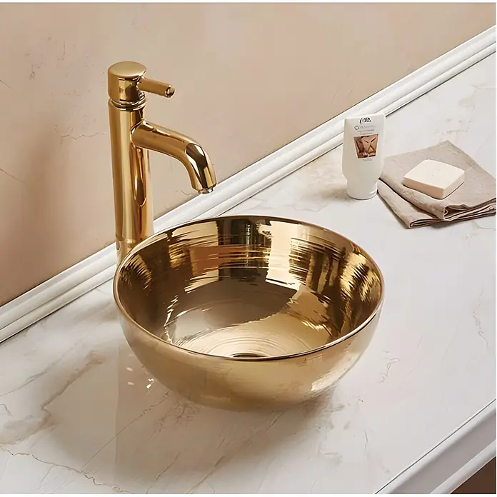 Sanicomfort Aufsatzwaschbecken Osiris - 35,8 x 35,8 cm, Hahnloch: Ohne, Ohne Überlauf, Gold Glänzend - Goldene Badarmatur und Waschbeckenschale auf einer Marmorarbeitsplatte.