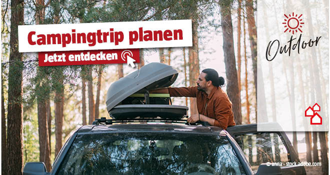 Mann räumt etwas aus der Dachbox vom Auto heraus, rundherum Wald