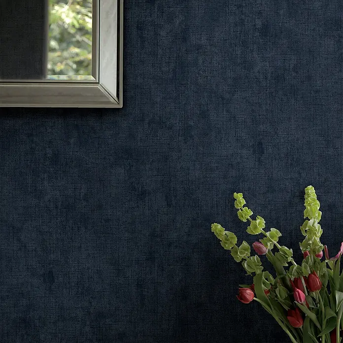 Laura Ashley Vliestapete Uni - Blau, Uni, 1.000 x 52 cm - Dunkelblaue strukturierte Tapete an einer Wand, mit Spiegel und Blumen.