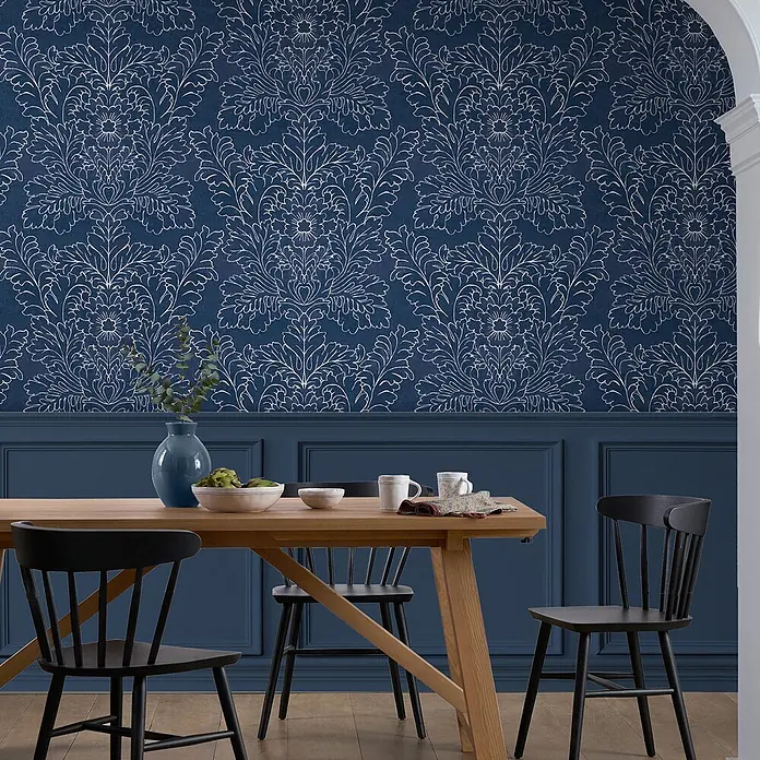 Laura Ashley Vliestapete Silchester - Blau, Floral, 1.000 x 52 cm - Esszimmer mit blauer Damasttapete, passender Wandvertäfelung, einem Holztisch und schwarzen Stühlen.