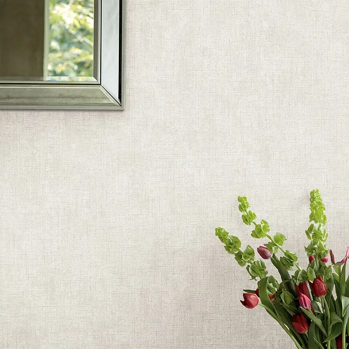 Laura Ashley Vliestapete Einfarbig - Grau, Uni, 1.000 x 52 cm - Hellbeige, texturierte Tapete an einer Wand, hinter einem Spiegel und Blumenstrauß.