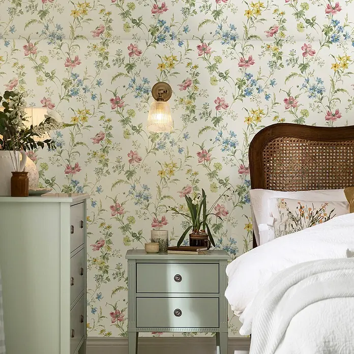 Laura Ashley Vliestapete Mohnwiese - Mehrfarbig, Floral, 1.000 x 52 cm - Florale Tapete mit rosa, blauen und gelben Blumen in einem Schlafzimmer.