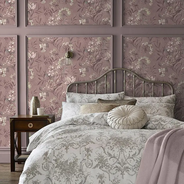 Laura Ashley Vliestapete Blairmore Blumen - Lila, Floral, 1.000 x 52 cm - Schlafzimmer mit Bett, weiß-grauer Zierbettwäsche, helllila Überwurf und malvenfarbener Blumentapete.