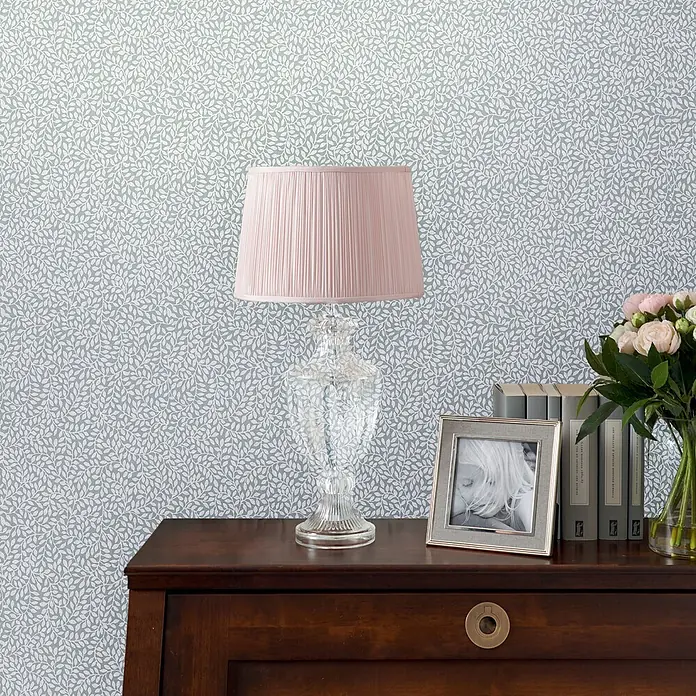 Laura Ashley Vliestapete Vliestapete Kleine Weinreben - Blau, Floral, 10 x 0,52 m - Zarte salbeigrüne Tapete mit wiederholtem weißem Blattmuster, an einer Wand hinter einem Holzschreibtisch angebracht.
