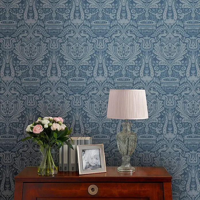 Laura Ashley Vliestapete Vliestapete Heraldic Damast - Blau, Sonstiges, 10 x 0,52 m - Blaue Tapete mit einem aufwendigen, hellgrauen Ornamentmuster, an einer Wand in einer Raumkulisse gezeigt.