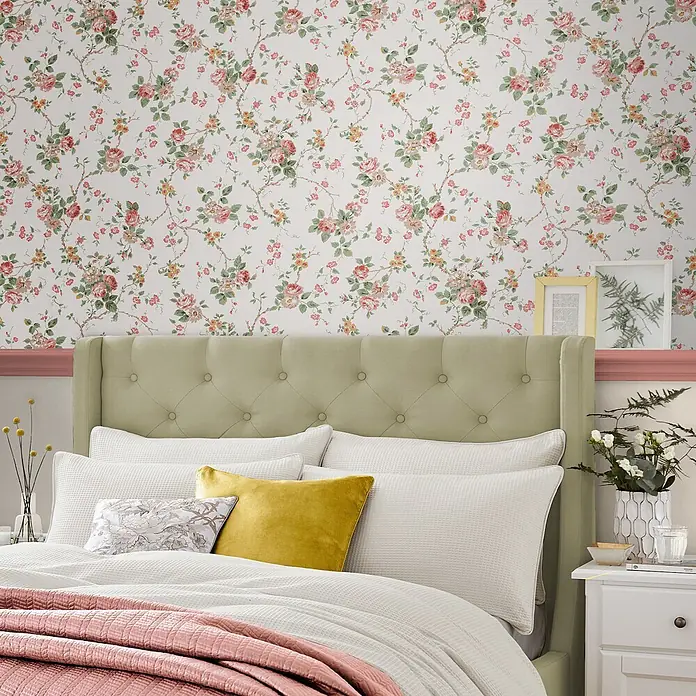 Laura Ashley Vliestapete Mountney Garten - Rosa, Floral, 1.000 x 52 cm - Florale Tapete mit rosa, roten und gelben Rosen und grünen Blättern, die ein Schlafzimmer schmückt.