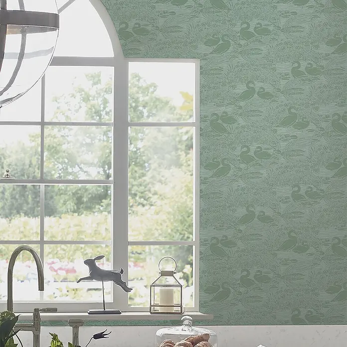 Laura Ashley Vliestapete Schwäne - Grün, Tieroptik, 1.000 x 52 cm - Grünes Wandpapier mit wiederkehrendem Muster aus Enten und Wasserpflanzen, angebracht an einer Wand neben einem Küchenfenster.