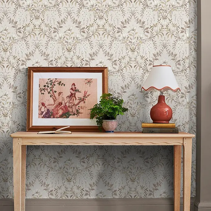 Laura Ashley Vliestapete Vintage Blumen - Naturbelassen, Floral, 1.000 x 52 cm - Tapete mit kunstvollem Blumen- und Rankenmuster in sanften Beige-, Braun- und Cremetönen an einer Wand hinter einer Konsole.