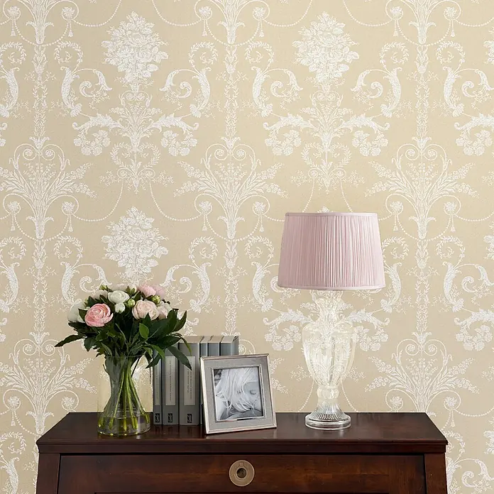 Laura Ashley Vliestapete Josette Damast - Leinen, Floral, 1.000 x 52 cm - Beige Tapete mit ornamentiertem weißem Damastmuster, die eine Wand in einem Zimmer bedeckt.