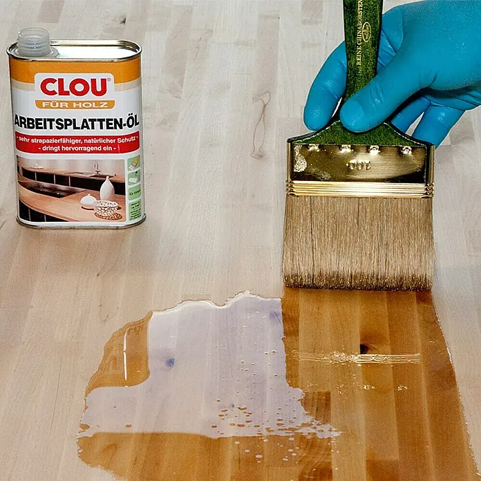 Clou Arbeitsplattenöl - 250 ml, Farblos - Dose CLOU Arbeitsplatten-Öl und Pinsel beim Auftragen auf eine Holzoberfläche. Schützt und betont die natürliche Schönheit des Holzes.