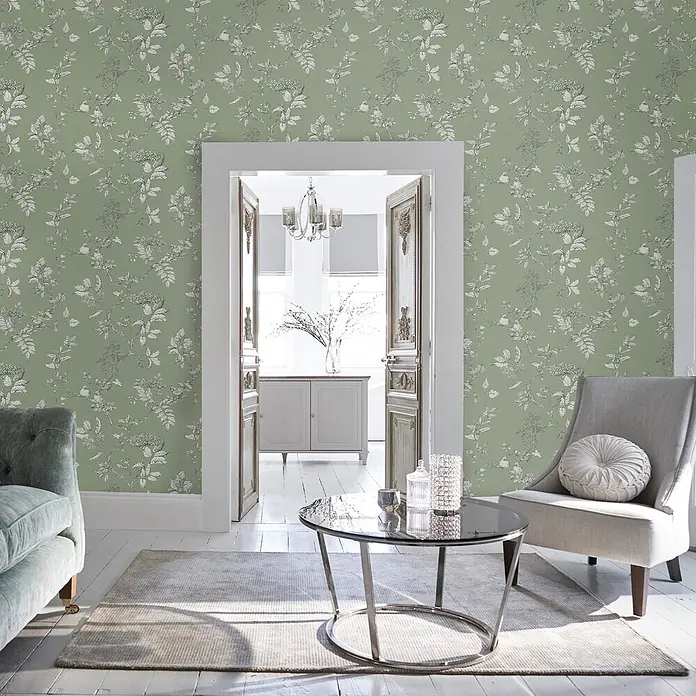Laura Ashley Vliestapete Vliestapete Elderwood - Salbeigrün, Floral, 10 x 0,52 m - Grüne Tapete mit weißem Blumen- und Vogelmuster, in einem Wohnzimmer.