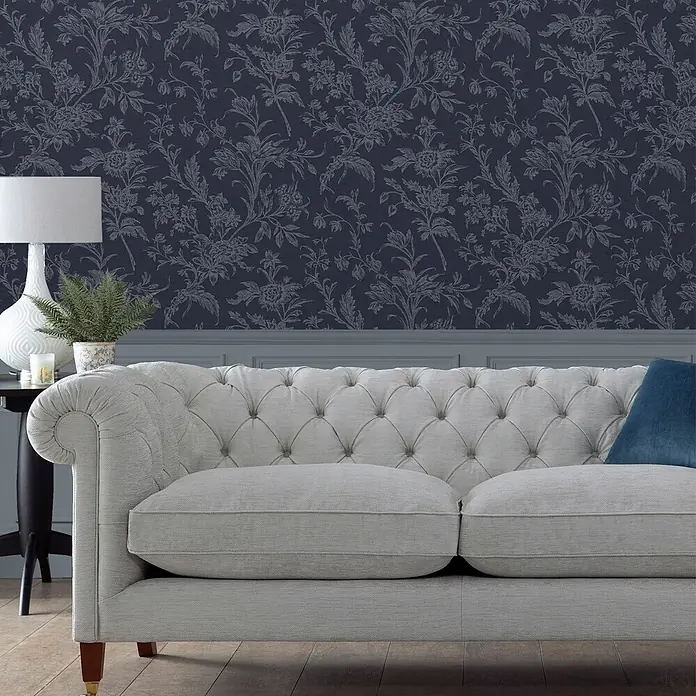 Laura Ashley Vliestapete Vliestapete Lloyd - Blau, Floral - Helles graues Polstersofa mit getufteter Rückenlehne und strukturiertem Stoff in Wohnzimmerumgebung.