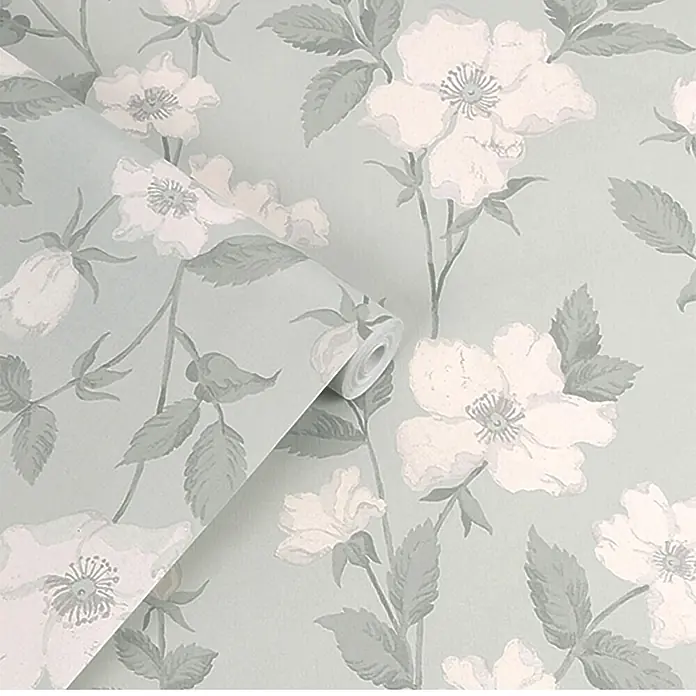 Laura Ashley Vliestapete Vliestapete Fleurir - Grün, Floral, 10 x 0,52 m - Hellblaue Tapetenrolle mit weißem Blumen- und graugrünem Blättermuster, teilweise abgerollt.