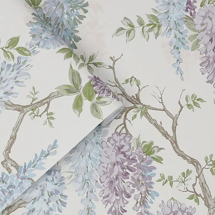 Laura Ashley Vliestapete Glyziniengarten - Blau/Rosa, Floral, 1.000 x 52 cm - Tapete mit blauen und lila Glyzinienblüten, grünen Blättern und braunen Zweigen auf cremefarbenem Hintergrund, teilweise abgerollt.