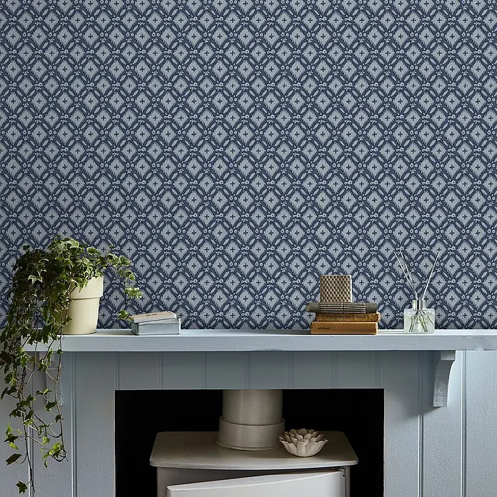 Laura Ashley Vliestapete Whitebrook - Blau, Floral, 1.000 x 52 cm - Blau-hellgraue Tapete mit geometrischem Ikat-Muster an einer Wand über einem hellblauen Kaminsims.