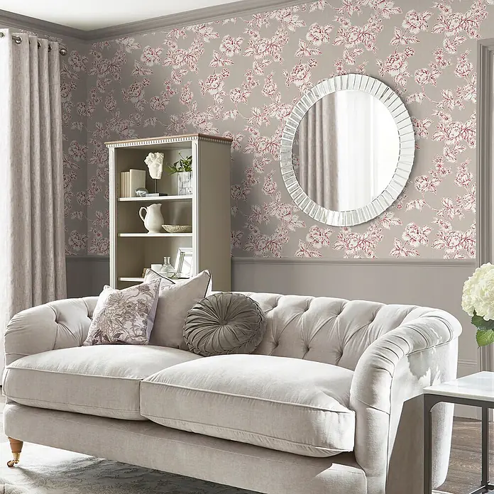 Laura Ashley Vliestapete Pollington rosen - Grau, Floral, 1.000 x 52 cm - Ein helles, getuftetes Stoffsofa mit Zierkissen in einem gemütlichen Wohnzimmer.