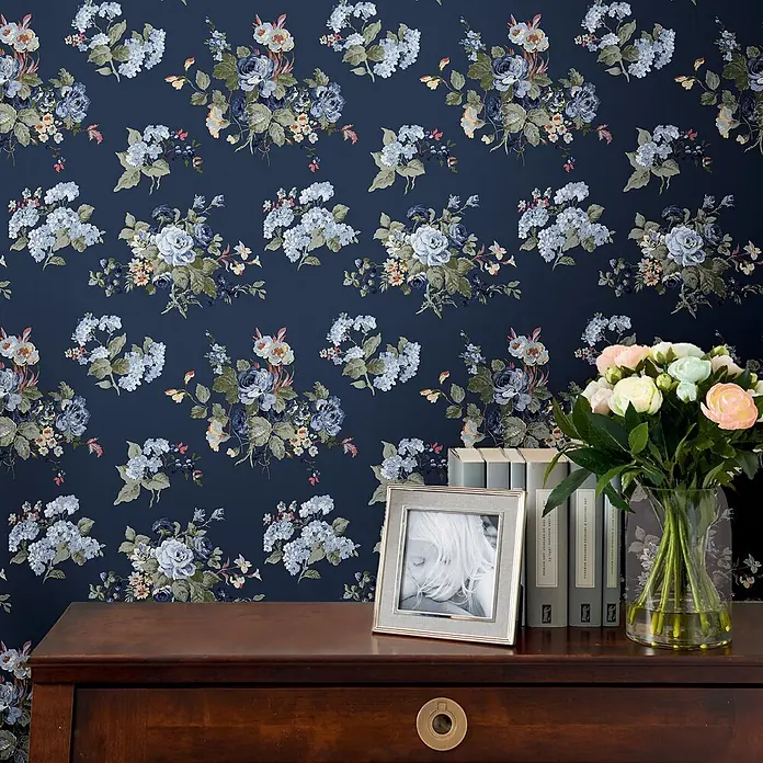 Laura Ashley Vliestapete Rosemore - Blau, Floral, 1.000 x 52 cm - Florale Tapete mit dunkelblauem Hintergrund und hellblauen, weißen und pfirsichfarbenen Blumen an einer Wand.