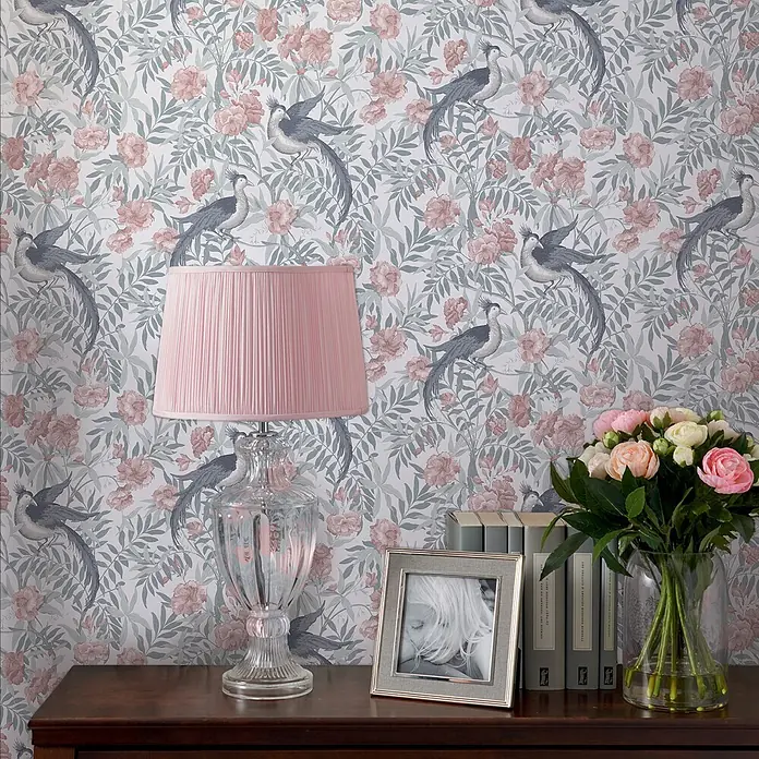 Laura Ashley Vliestapete Vliestapete Osterley - Blau/Rosa, Tieroptik, 10 x 0,52 m - Tapete mit einem Muster aus blaugrauen Vögeln, rosa-malvenfarbenen Blüten und Blättern an einer Wand in einem Raum.